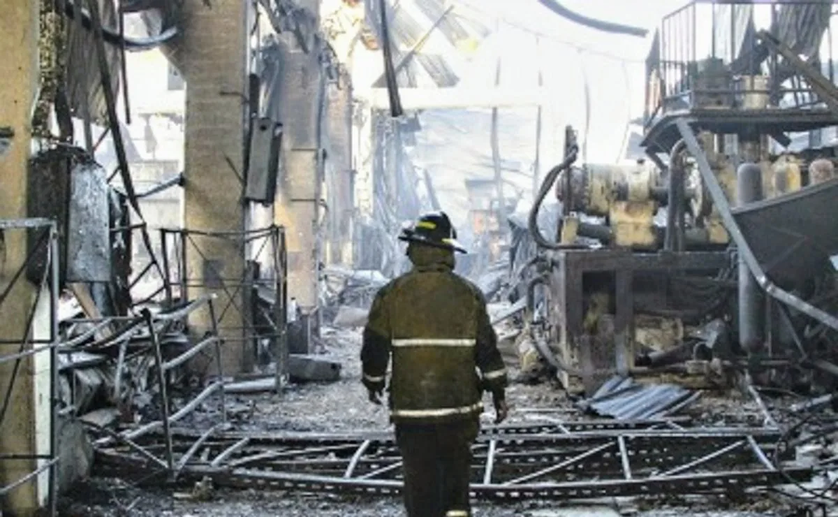 La planta de Gemplast destruida por el incendio de 2015, con un bombero recorriendo lo que quedó de la nave